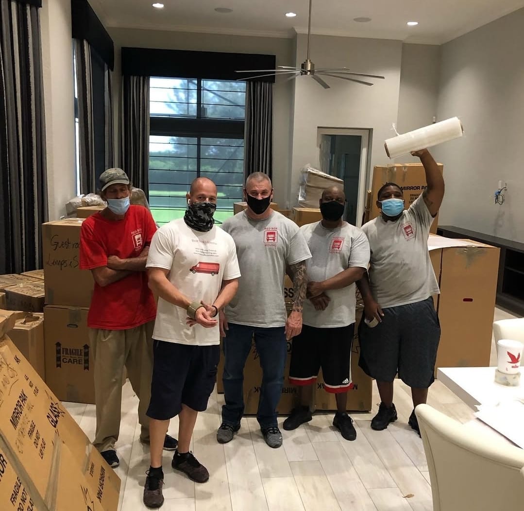 Red Box Moving crew with branded shirts surrounded by packed boxes