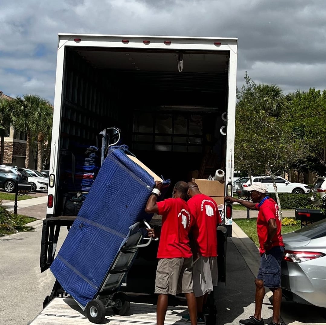 Red Box Moving crew loading furniture into the truck in a residential driveway
