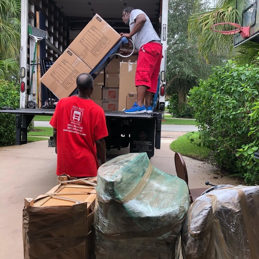 Red Box Moving crew loading boxes and wrapped furniture into the truck